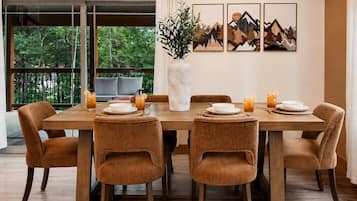 Un coin repas avec une table en bois, six chaises et un vase agrémenté de plantes vertes.