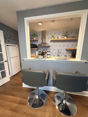 A modern kitchen with a central island, two bar stools, and a microwave.