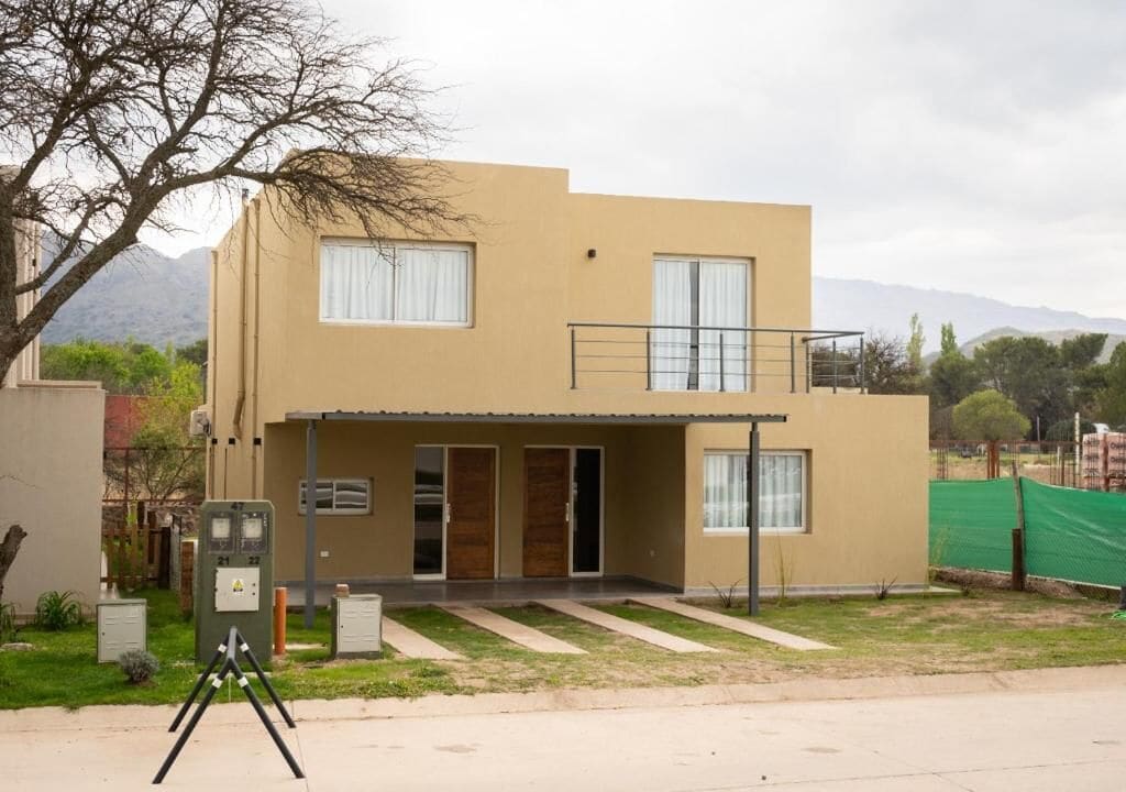 Un edificio de dos plantas con techo plano, un balcón en el piso superior y un pequeño porche delantero.
