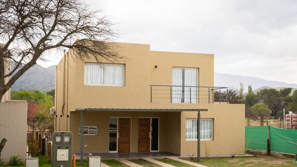 A two-story building with a flat roof, a balcony on the upper floor, and a small front porch. - Hotel Cantera Respira Campo (Las Chacras)