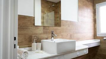 A bathroom with a white sink, a mirror, and a shower area.