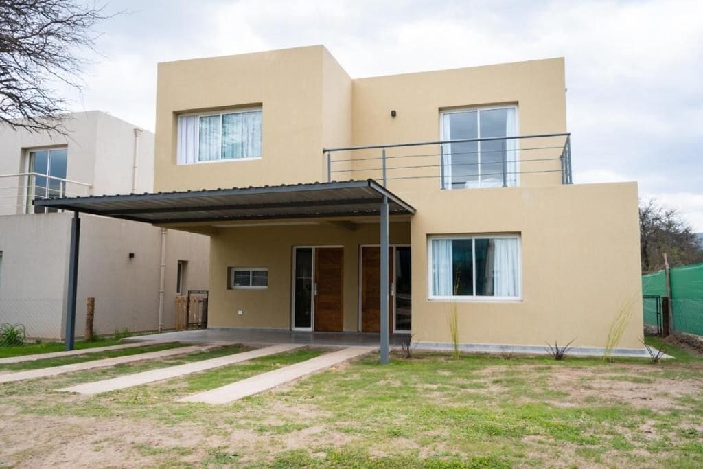 Un edificio residencial de dos pisos con un porche cubierto y una puerta principal visible.