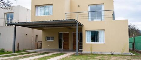 A two-story residential building with a covered patio area and a visible front door.