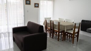 A room with a sofa, dining table with chairs, and an air conditioning unit. - Hotel Cantera Respira Campo (Las Chacras)