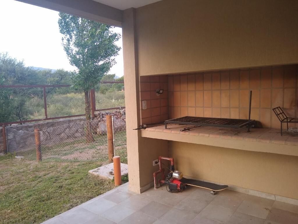 An outdoor patio area with a barbecue grill, a chair, and a power tool on the ground.