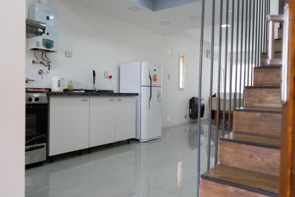 Una cocina moderna con armarios blancos, un horno de acero inoxidable, un refrigerador blanco y una cafetera en la encimera.