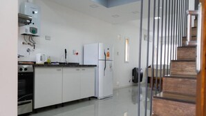 A modern kitchen with white cabinets, a stainless steel oven, a white refrigerator, and a coffee maker on the counter. - Hotel Cantera Respira Campo (Las Chacras)