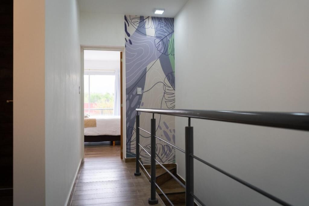 Un couloir au design moderne, doté d’une main courante en métal et d’un mur orné de motifs.