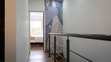 Un couloir au design moderne, doté d’une main courante en métal et d’un mur orné de motifs.