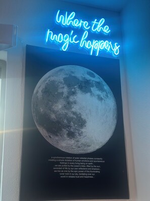 Un cartel con la luna y un letrero de neón que dice 'Donde ocurre la magia'.