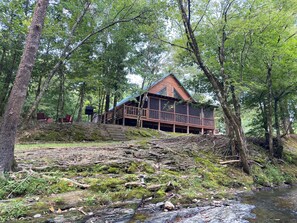 A cabin with a deck, surrounded by trees and a stream. - The Wilson Pine- A Private Cabin Retreat (Norman)