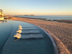 Ein Strand mit Pool und einer Promenade.