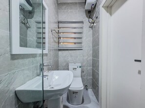 A bathroom with a white sink, toilet, and a glass shower enclosure. - Radiant Studio Apartment in Victoria Island with Pool, Fast Wi-Fi & 24/7 Power (Lagos)