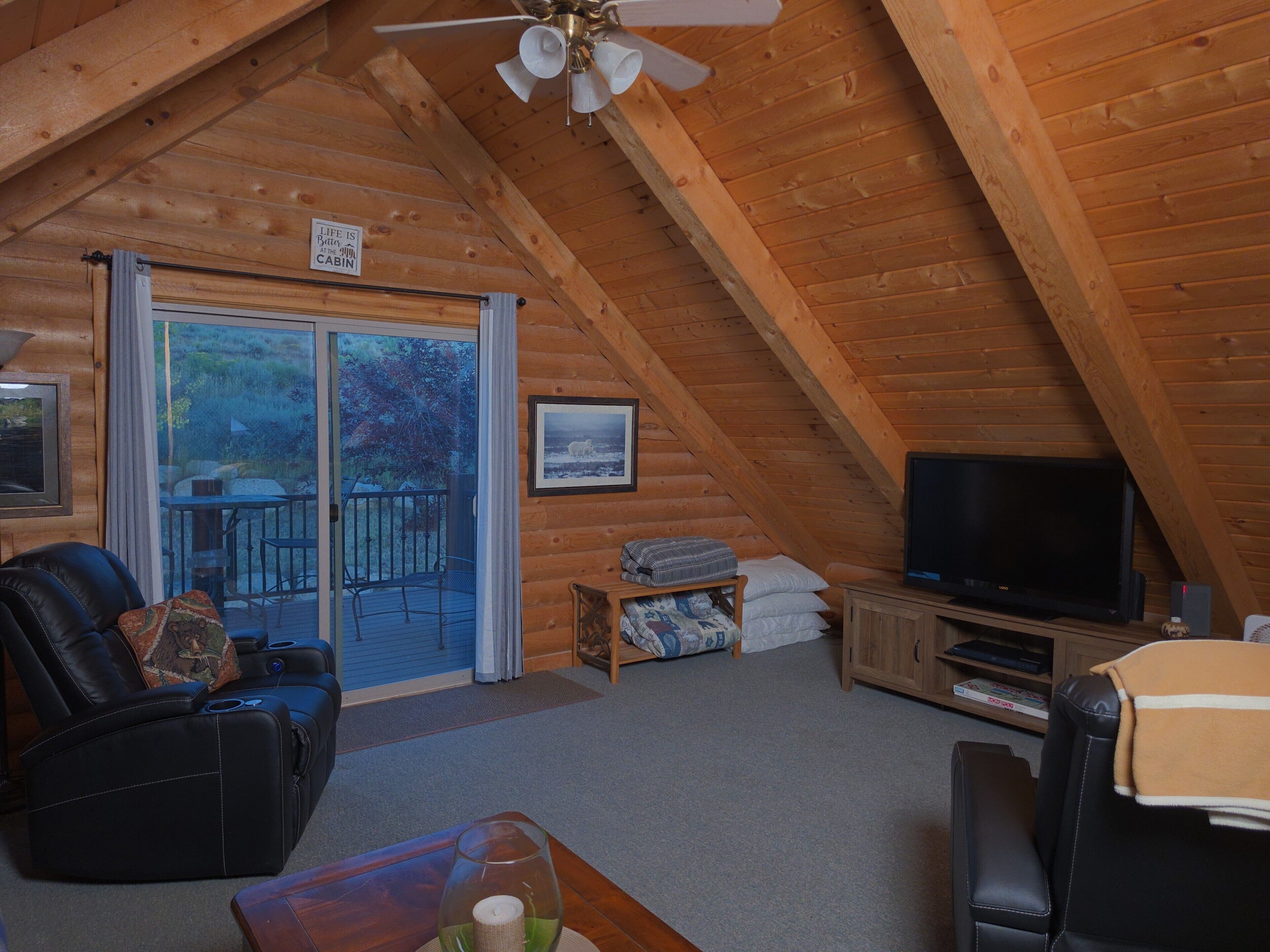 A cozy cabin interior with a television, seating area, and a view through the sliding glass door.