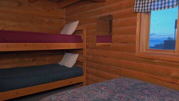 Une cabine équipée de deux lits superposés et d’un lit simple, avec des murs en bois, une fenêtre donnant sur un paysage agréable et un rideau à carreaux.