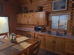 L’intérieur d’une cabane en bois comprend un coin cuisine équipé de meubles en bois, d’un four à micro-ondes et d’un évier.