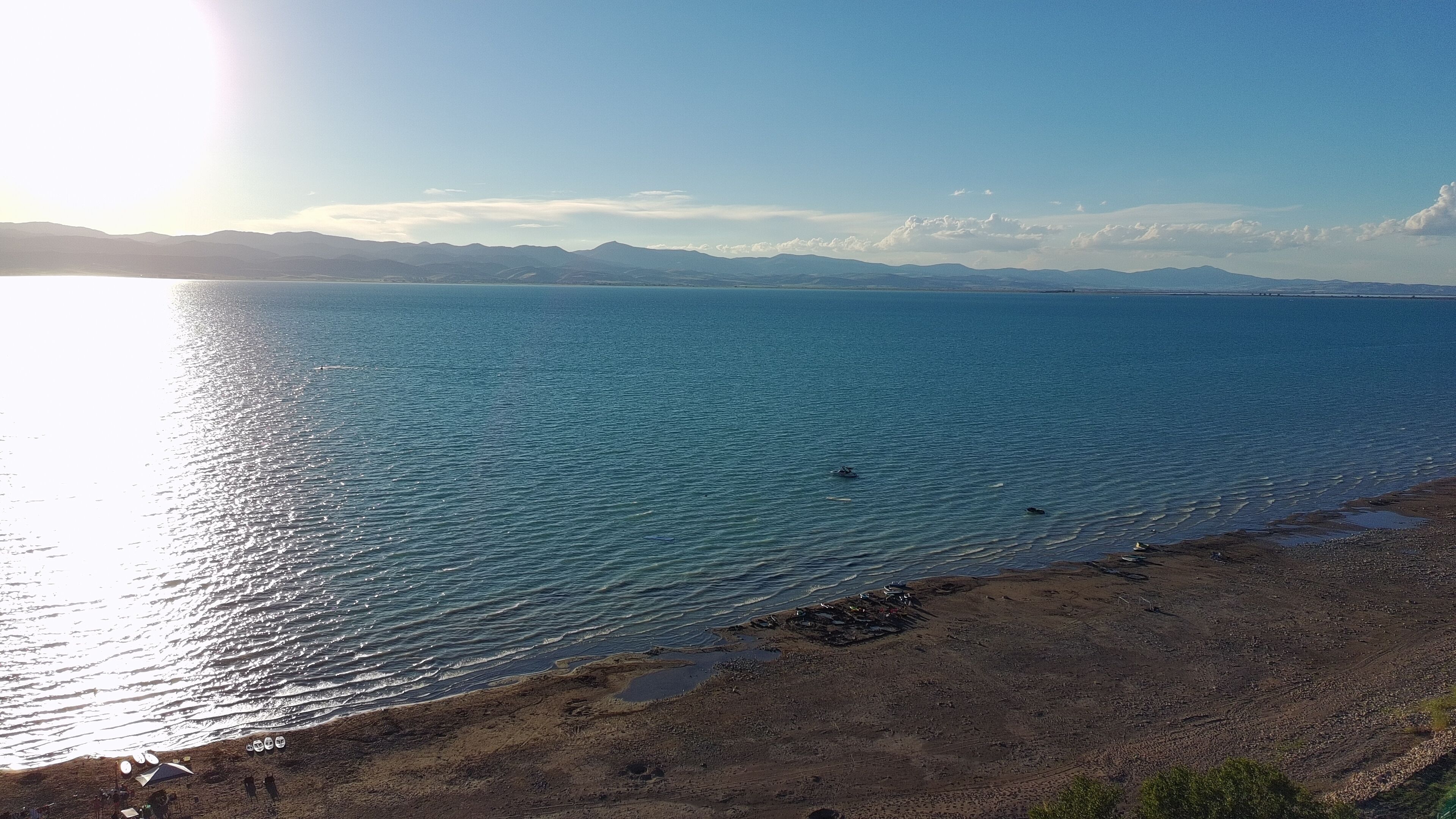 Un paisaje costero con playa, mar tranquilo y montañas a lo lejos.
