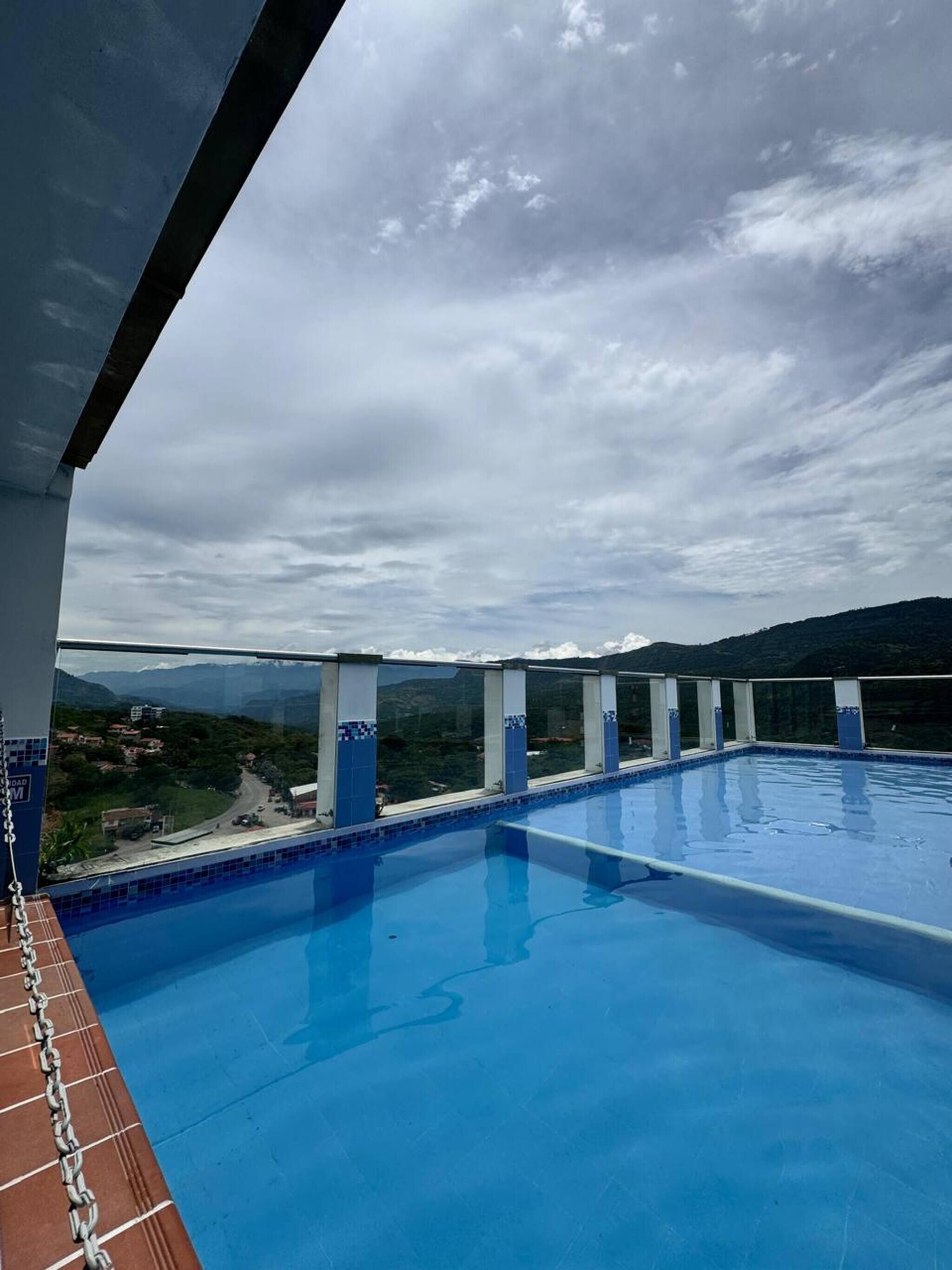 A rooftop pool with a view of a hilly landscape.