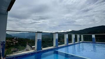 A rooftop pool with a view of a hilly landscape.