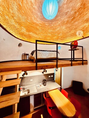 A circular room with a bunk bed, a desk, and a chair.