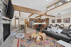 A spacious living area with a fireplace, a sofa, a coffee table, and a dining area with chairs. - Alpine Retreat Near Winter Park Resort (Winter Park)