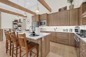 A modern kitchen with wooden cabinets, stainless steel appliances, and a central island with seating. - Alpine Retreat Near Winter Park Resort (Winter Park)