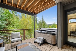 A wooden deck with a hot tub, a chair, and a table. - Alpine Retreat Near Winter Park Resort (Winter Park)