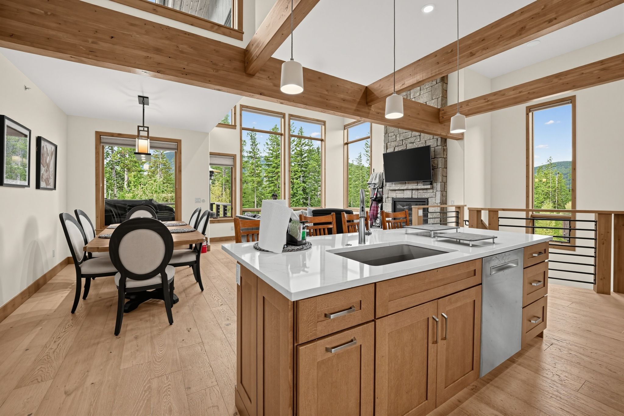 A modern kitchen with a large island, wooden cabinets, and a stone fireplace.