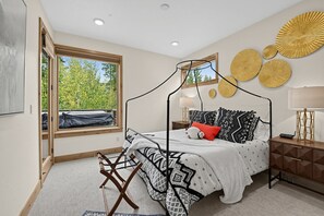 A bedroom with a four-poster bed, a window with a view of trees, a bedside table with a lamp, and a wall with decorative plates. - Alpine Retreat Near Winter Park Resort (Winter Park)