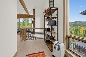 Een modern interieur met een houten trap, een metalen leuning en een groot raam met uitzicht op een bergachtig landschap.