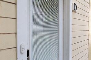 Eine weiße Tür mit Fenster, Klingel und Briefkasten an einer beige verputzten Wand.