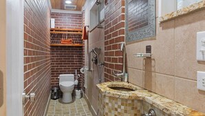 A narrow bathroom with a toilet, shower, and a sink with a mosaic tile design. - The longest bathroom in GNV! (Gainesville)