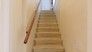 A carpeted staircase with a wooden handrail, leading to an upper floor. - The longest bathroom in GNV! (Gainesville)