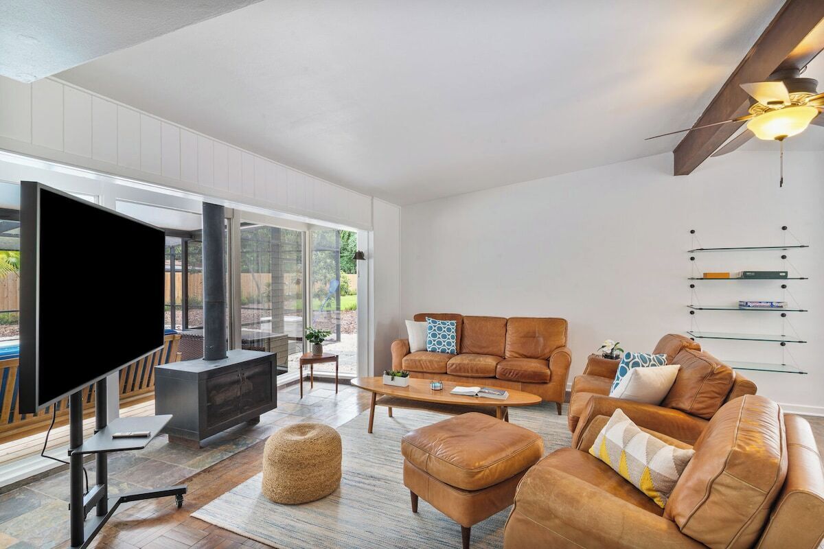 A modern living room with a flat-screen TV, leather sofas, a coffee table, and a fireplace.