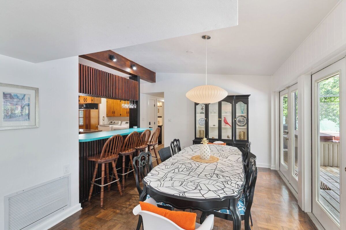 A dining area with a large table, chairs, and a hanging light fixture.