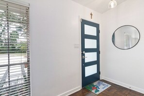 A door with frosted glass panels, a round mirror on the wall, and a doormat with a cartoon character. - Gator Pool Home - Close to UF (Gainesville)