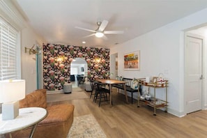 A dining area with a table and chairs, a ceiling fan, and a floral wallpaper. - Happy College Home + Patio and Parking (Gainesville)