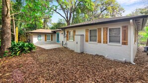 Ein eingeschossiges Haus mit Veranda, Garage und einem mit Rindenmulch bedeckten Garten.