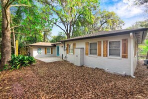 Ein eingeschossiges Haus mit Veranda, Garage und einem mit Rindenmulch bedeckten Garten.