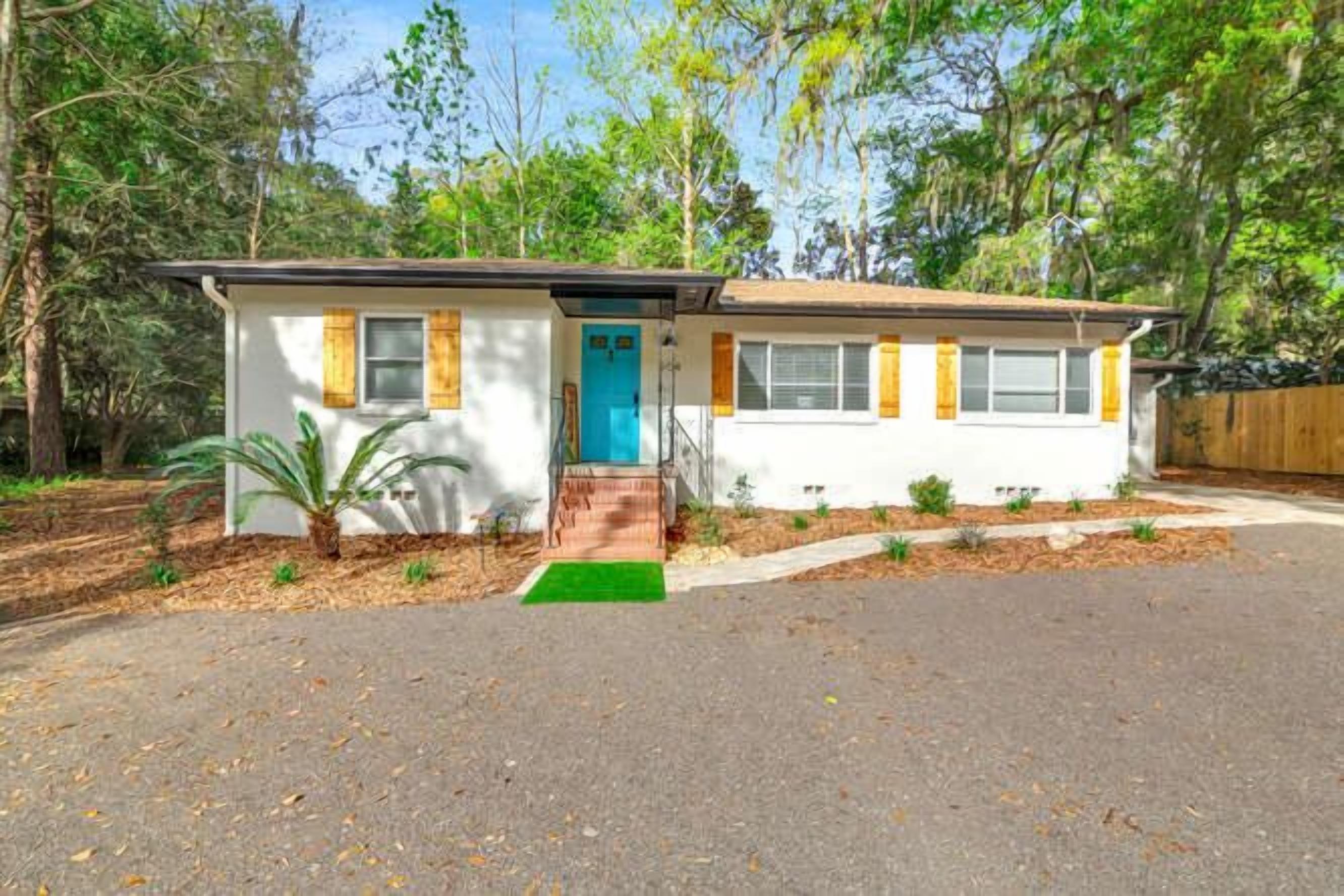 A single-story house with a front porch, a blue door, and a small front yard.