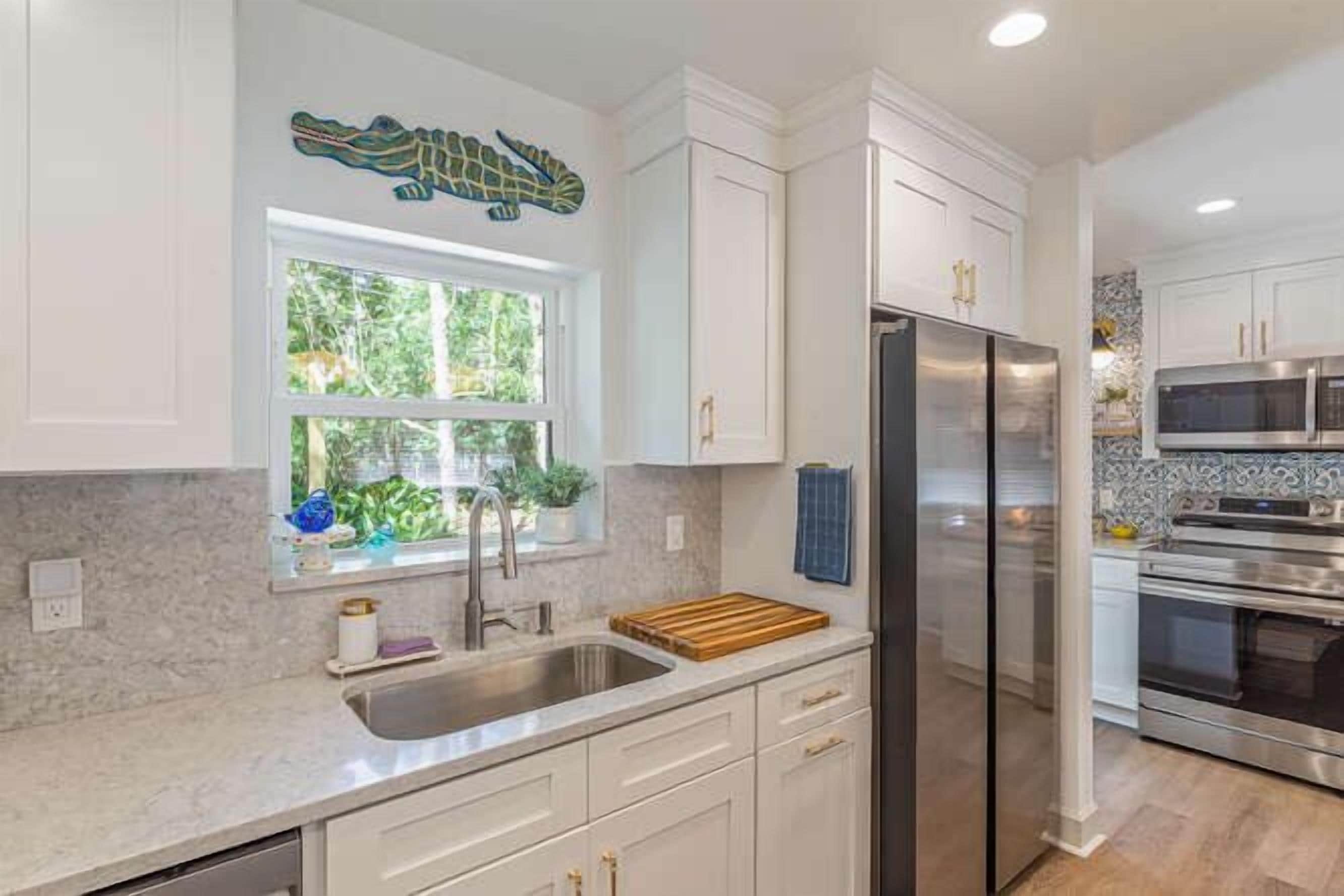 A kitchen with white cabinets, a stainless steel refrigerator, and a microwave.
