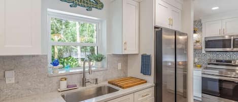 A kitchen with white cabinets, a stainless steel refrigerator, and a microwave.