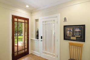 A hallway with a wooden door, a white door, and a framed picture on the wall. - Large 1 Gator_room Apt near UF! (Gainesville)