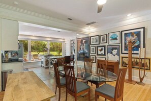 A dining area with a glass table surrounded by wooden chairs, a kitchen area with modern appliances, and a view of the outdoors. - Large 1 Gator_room Apt near UF! (Gainesville)