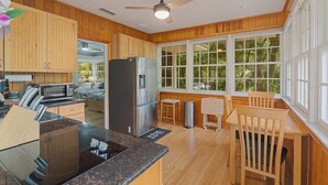 A kitchen with wooden cabinets, a stainless steel refrigerator, a microwave, and a dining area with a wooden table and chairs. - Quaint and Quiet near UF! (Gainesville)