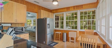 A kitchen with wooden cabinets, a stainless steel refrigerator, a microwave, and a dining area with a wooden table and chairs.