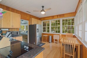 A kitchen with wooden cabinets, a stainless steel refrigerator, a microwave, and a dining area with a wooden table and chairs. - Quaint and Quiet near UF! (Gainesville)