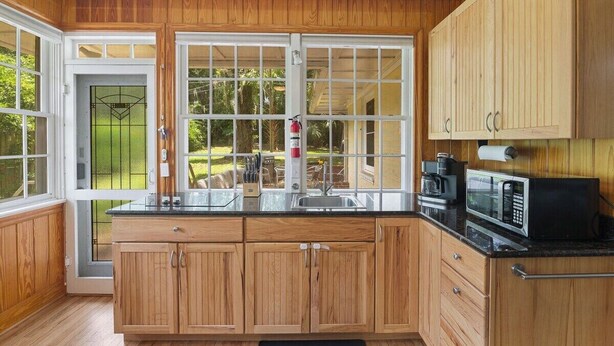 A kitchen with wooden cabinets, a microwave, and a sink. - Quaint and Quiet near UF! (Gainesville)