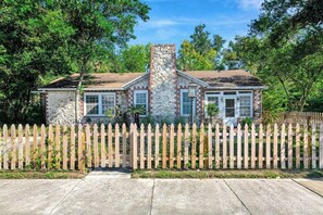 A two-story house with a stone chimney, a picket fence, and a well-maintained lawn. - The Gainesville Rock House (Gainesville)