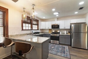 A kitchen with a central island, stainless steel appliances, and a patterned rug. - The Gainesville Rock House (Gainesville)